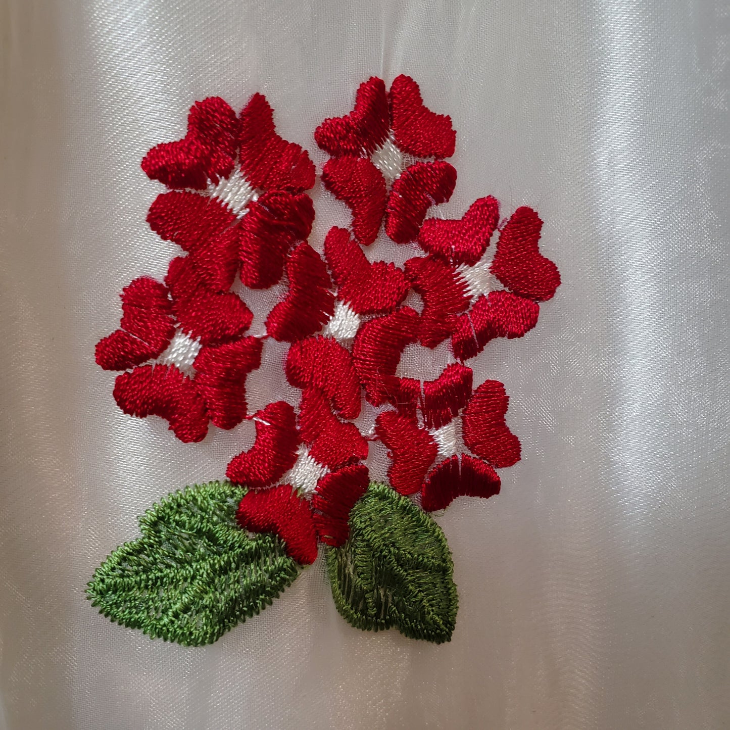 Vestido de niña pequeña con flores rojas sobre fondo blanco y cárdigan a juego